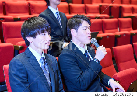 講演会の客席で積極的に質問をするスーツ姿の男性と参加者 講演会の客席で積極的に質問をするスーツ姿の男性と参加者 143268270