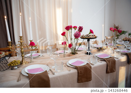 Festive dinner table setting with pink floral arrangements and candelabra Festive dinner table setting with pink floral arrangements and candelabra 143268446
