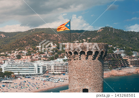 Estelada flag above coastal tower in Catalonia Spain with Costa Brava landscape and seaside resort town. Editorial travel image about Catalan independence and regional identity 143268501