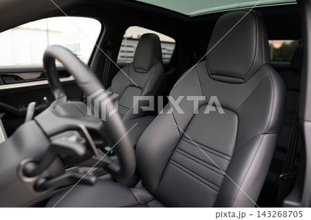Interior view of luxury car front black leather seats and steering wheel Interior view of luxury car front black leather seats and steering wheel 143268705