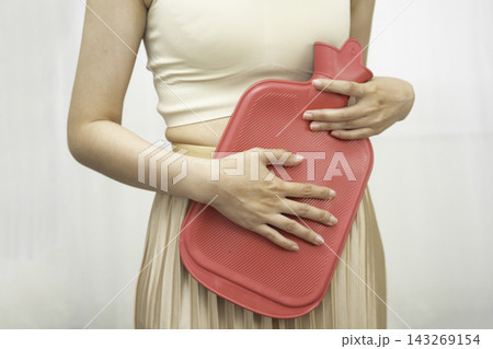 Woman using hot water bottle to relieve menstrual abdominal pain. 143269154