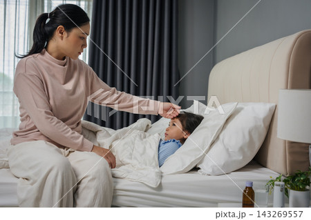 mother take care and checking forehead temperature of sick preschool child girl in bed 143269557