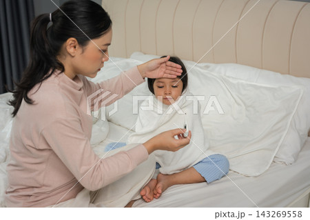mother using thermometer measuring temperature to checking fever of sick preschoool child girl while hand touching forehead in bed 143269558