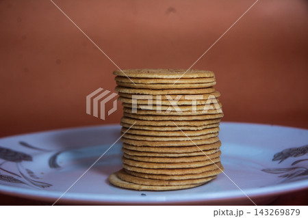 Tall Stack of Round Golden Biscuits Placed on a White Ceramic Plate Featuring Warm Lighting Tall Stack of Round Golden Biscuits Placed on a White Ceramic Plate Featuring Warm Lighting 143269879