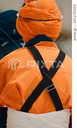 Indian man in orange uniform and turban prays during Vaisakhi 143270264