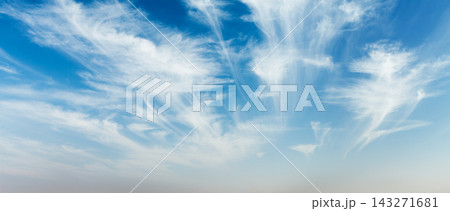A serene sky filled with fluffy clouds stretches across a clear blue backdrop, providing a tranquil scene during the daytime. 143271681