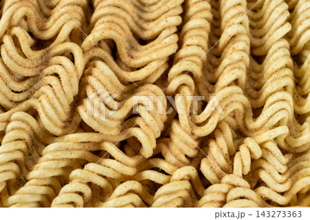 Macro shot of dry instant ramen noodles sprinkled with seasoning powder and herbs Macro shot of dry instant ramen noodles sprinkled with seasoning powder and herbs 143273363