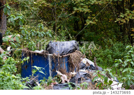 Garbage container and plastic trash bags polluting green forest or park  143273693