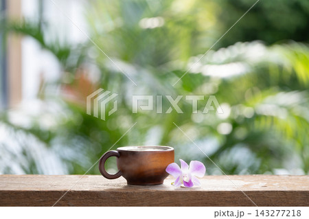 Dark brown wooden cup and purple orchid flower on wooden table Dark brown wooden cup and purple orchid flower on wooden table 143277218