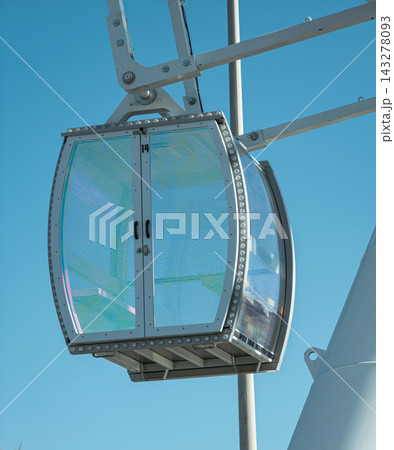 Enclosed glass Ferris wheel gondola number suspended against blue sky Enclosed glass Ferris wheel gondola number suspended against blue sky 143278093