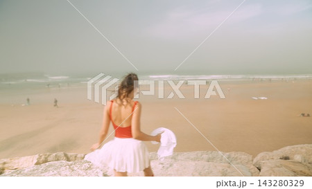 Seaside woman in sunset. Female standing by ocean at dusk Seaside woman in sunset. Female standing by ocean at dusk 143280329