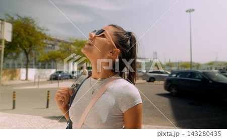 Woman with open smile reveling in warm sun at waterfront location 143280435