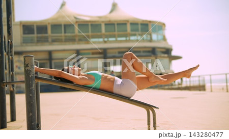 Individual performs gentle stretch facing ocean pavilion Individual performs gentle stretch facing ocean pavilion 143280477