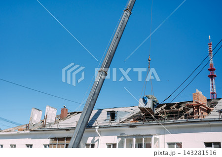 Mobile crane lifting construction materials during roof renovation of residential building 143281516