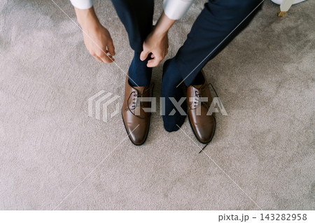 Man putting on brown leather dress shoes 143282958
