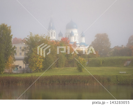 Scenic autumn landscape of Pokrovsky cathedral in Gatchina shrouded in thick morning fog with peaceful lake reflection, Leningrad oblast, Russia. Scenic autumn landscape of Pokrovsky cathedral in Gatchina shrouded in thick morning fog with peaceful lake reflection, Leningrad oblast, Russia. 143283055