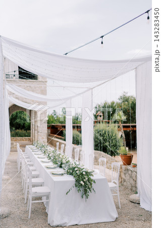 Chic riverside evening celebration. Chic riverside party with drapes lights and greenery decor Chic riverside evening celebration. Chic riverside party with drapes lights and greenery decor 143283450