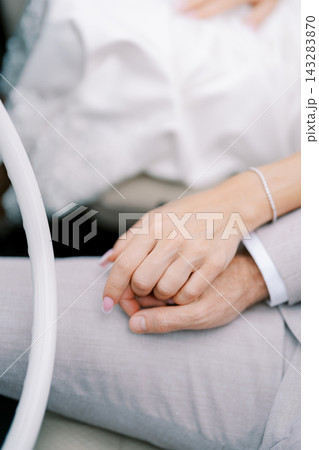 Intimate scene showing two hands clasped softly with wedding rings present Intimate scene showing two hands clasped softly with wedding rings present 143283870