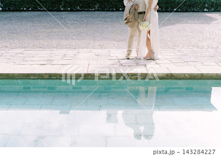 Elegant wedding couple standing by poolside 143284227