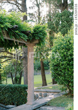 Stone Garden Pergola Surrounded by Lush Greenery Stone Garden Pergola Surrounded by Lush Greenery 143284316