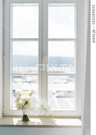White Roses and Orchids Bouquet on Sunlit Window Sill 143284935