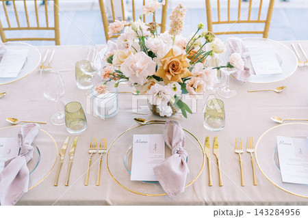 Chic pastel dining arrangement. Refined pastel reception display with elegant tableware and soft illumination Chic pastel dining arrangement. Refined pastel reception display with elegant tableware and soft illumination 143284956