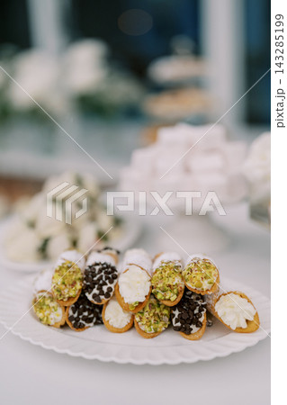 Charming collection of tiny desserts displayed on clean porcelain surface under soft lighting Charming collection of tiny desserts displayed on clean porcelain surface under soft lighting 143285199