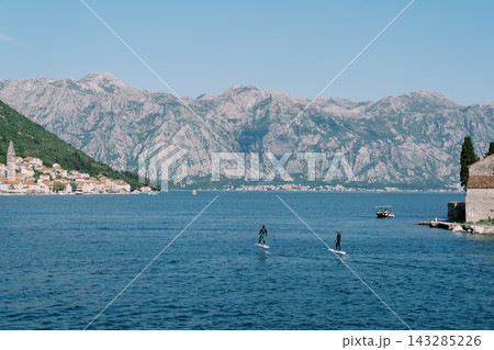 Serene paddleboarding over tranquil bay. Calm waters reflect peaceful seaside adventure moments Serene paddleboarding over tranquil bay. Calm waters reflect peaceful seaside adventure moments 143285226