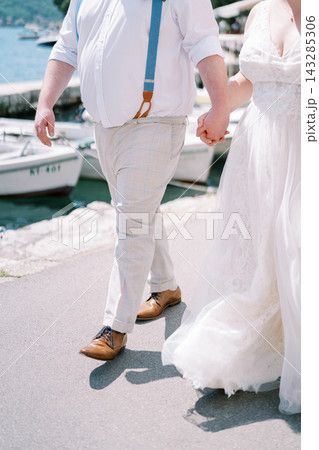 Couple by marina water. Sunlit romantic walk on shoreline with boats and smiling couple Couple by marina water. Sunlit romantic walk on shoreline with boats and smiling couple 143285306