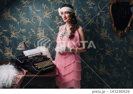 Elegant woman in 1920s style with magnolia flower and vintage typewriter Elegant woman in 1920s style with magnolia flower and vintage typewriter 143286926
