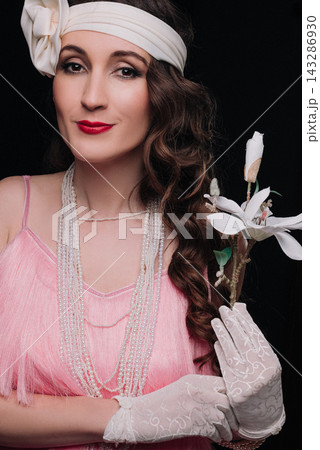 Elegant young woman and girl in 1920s style holding a white magnolia flower 143286930