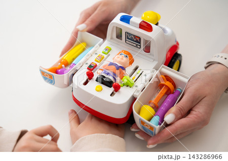 Close-up of a woman and child playing with an interactive toy ambulance 143286966