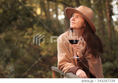 Woman with hat holding glass of red wine outdoors Woman with hat holding glass of red wine outdoors 143287139
