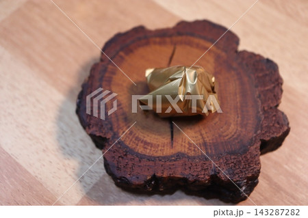 Golden Foil Wrapped Object on Wooden Slice 143287282