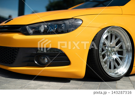 Close-up of yellow tuned sport car with custom chrome rims Close-up of yellow tuned sport car with custom chrome rims 143287316