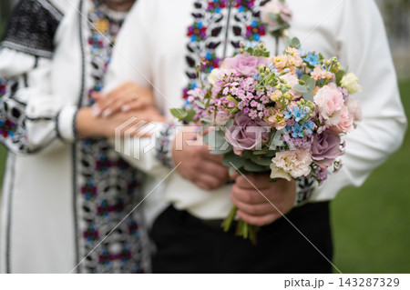 the bride and groom are holding hands with a bouquet of flowers and in traditional Ukrainian clothes the bride and groom are holding hands with a bouquet of flowers and in traditional Ukrainian clothes 143287329