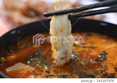 Chopsticks Holding Dumpling in Spicy Soup 143287476