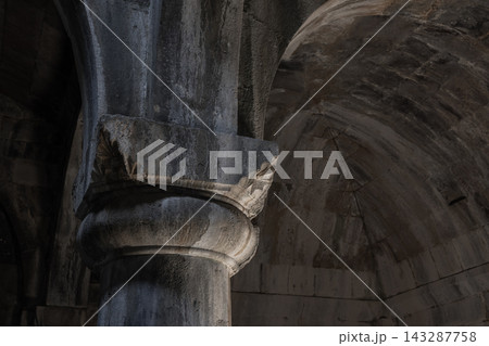 A close-up view of a weathered stone column and ornate capital beneath a vaulted arch 143287758
