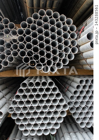Bundled metal pipes stacked in a hexagonal honeycomb pattern on a storage rack. 143288561