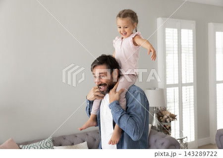 Overjoyed energetic loving dad carry laughing toddler daughter on shoulders Overjoyed energetic loving dad carry laughing toddler daughter on shoulders 143289722
