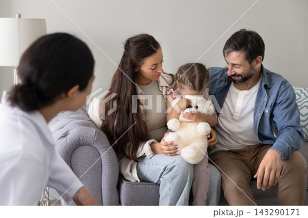 Little girl hiding face while parents and doctor comforting her 143290171