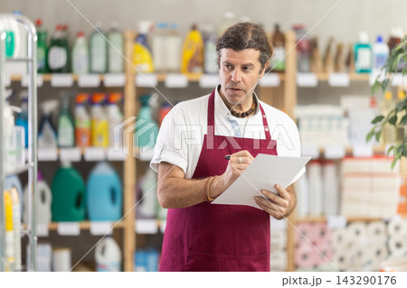 Adult man seller conducting inventory in store 143290176