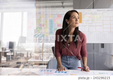Woman leans on table covered with data charts and reports Woman leans on table covered with data charts and reports 143290215