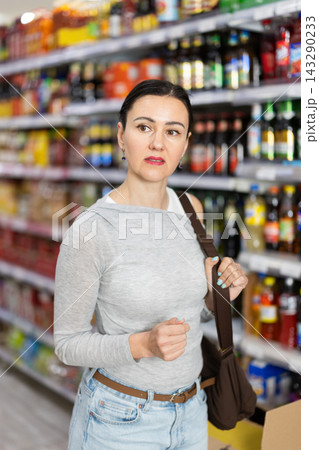 In food store, woman looking for something on shelf of showcase In food store, woman looking for something on shelf of showcase 143290233