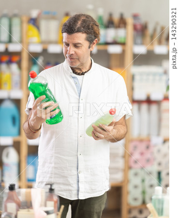 Adult man chooses dishwashing detergent in store Adult man chooses dishwashing detergent in store 143290321