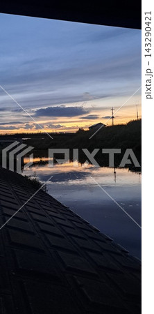 夕暮れの川面を染める夕焼けと橋のシルエット 夕暮れの川面を染める夕焼けと橋のシルエット 143290421