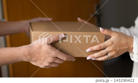 Close up cropped shot man woman hands holding cardboard box Close up cropped shot man woman hands holding cardboard box 143290422