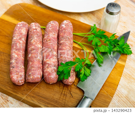 Fresh raw pork botifarra sausages ready on wooden cutting board Fresh raw pork botifarra sausages ready on wooden cutting board 143290423