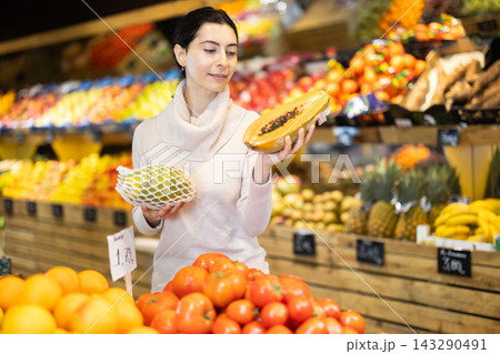 Young woman choosing papaya at vegetable shop Young woman choosing papaya at vegetable shop 143290491