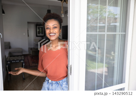 Smiling African woman welcoming guests at home Smiling African woman welcoming guests at home 143290512